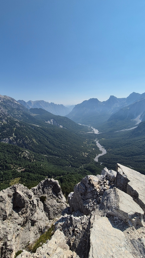 Long valley with a river running through it and mountains.