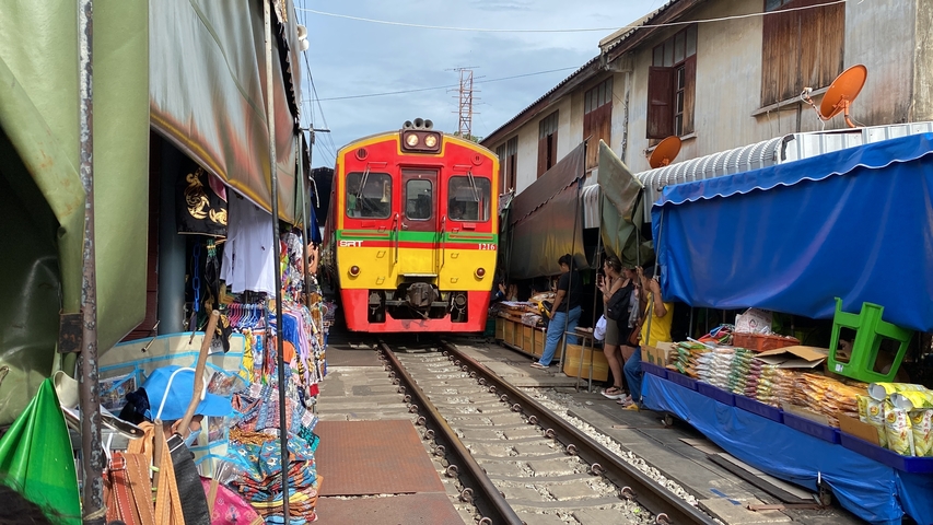       Train passing through a crowded market street.
  