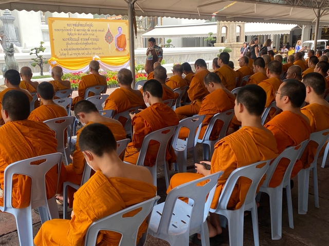 Group of Buddhist monks sitting on chairs in a ceremony.