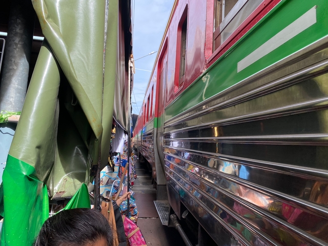       Trains moving closely beside each other through a market.
  
