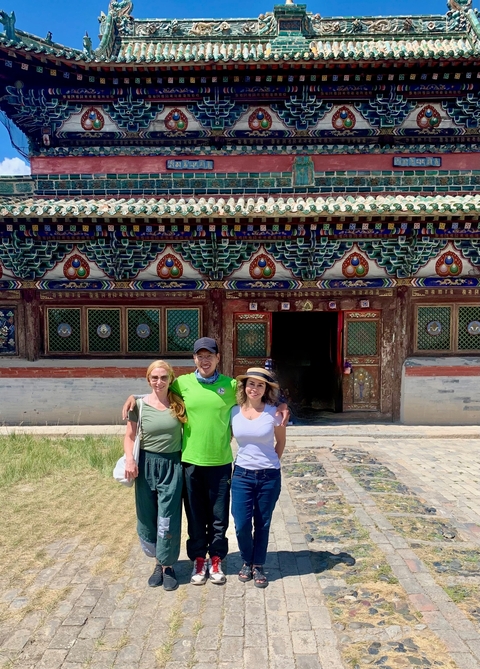 Three people posing in front of a decorated building.