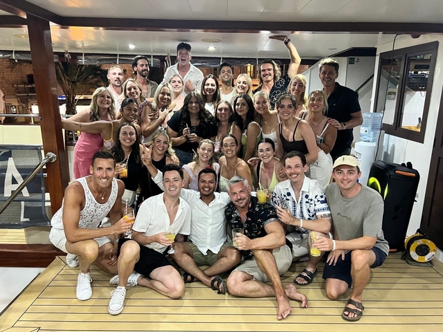       Large group of people on a boat having drinks.
  