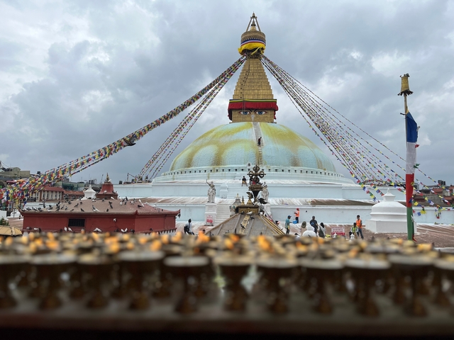 Stupa with colorful prayer flags and people in the background.