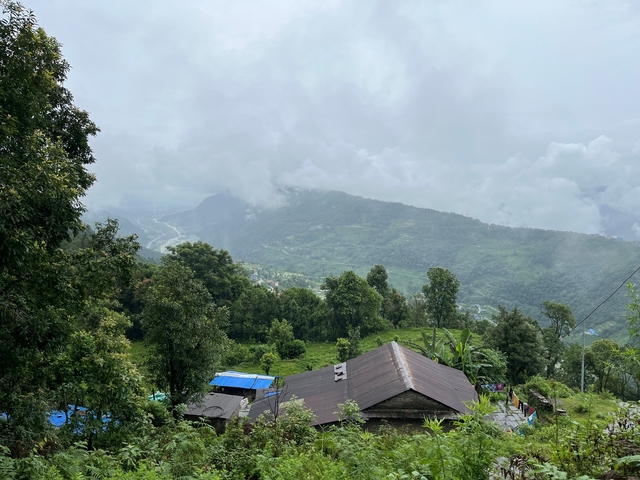       Hilly landscape with houses and cloudy sky.
  