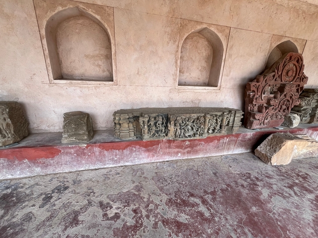 Stone carvings displayed on a pink wall.
