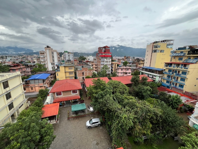       Aerial view of a city with greenery and mountains in the background.
  