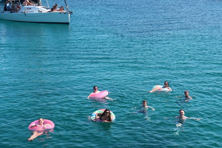 Group of people swimming in clear blue water.