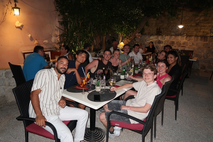 Group dining outdoors at evening, enjoying food and drinks.