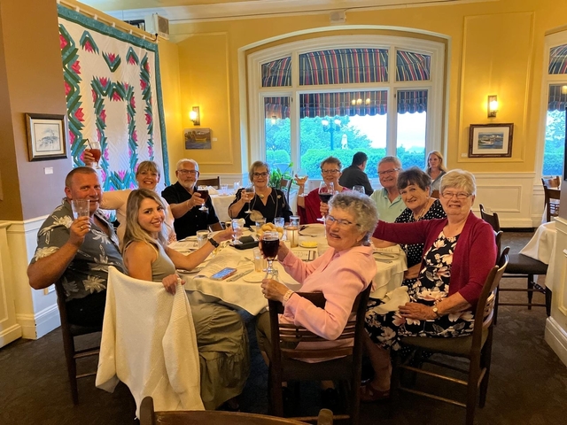       Group of people raising glasses at a dinner table.
  