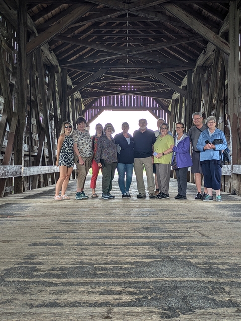 Group of people standing inside another covered bridge.
