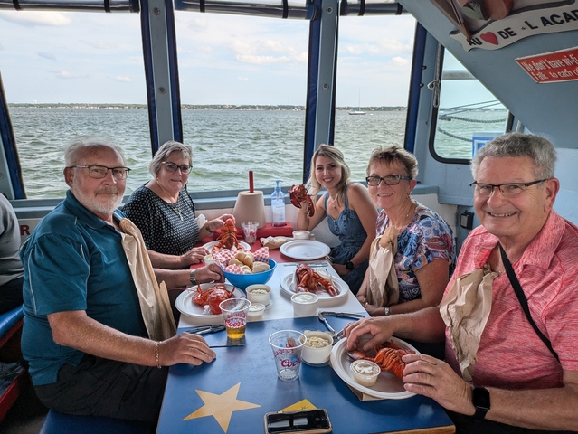 Group of people enjoying a lobster meal on a boat.