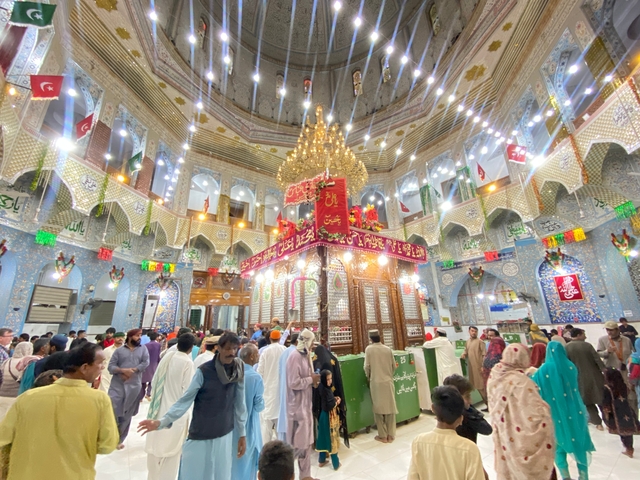       Interior of a shrine with ornate decorations and a large crowd
  