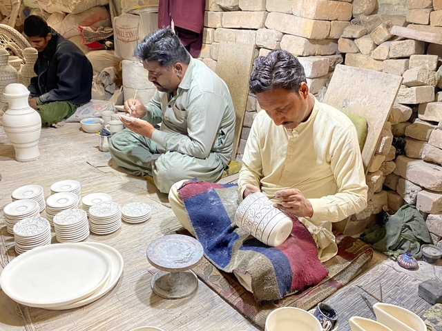 Artisans painting pottery pieces in a workshop setting