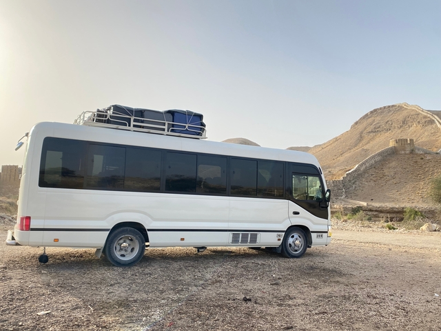 Travel bus parked with luggage on top in a desert terrain