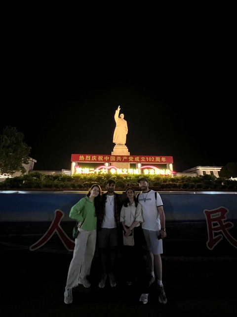 Group of people standing in front of a large statue with Chinese characters.