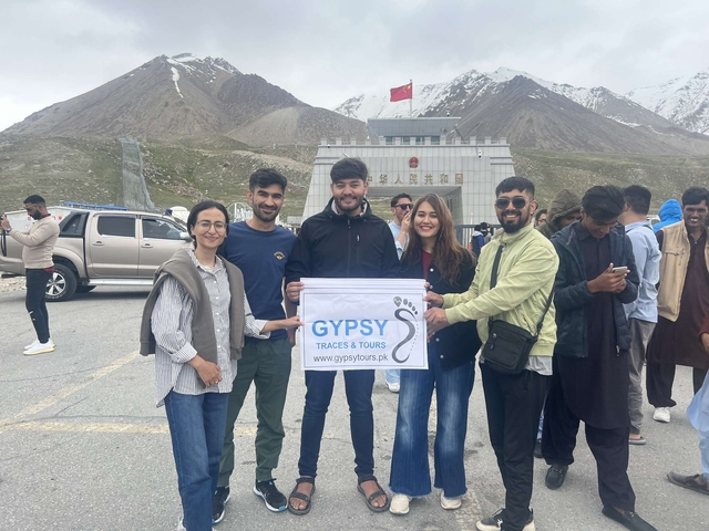 Group of travelers holding a banner in front of a mountain pass.