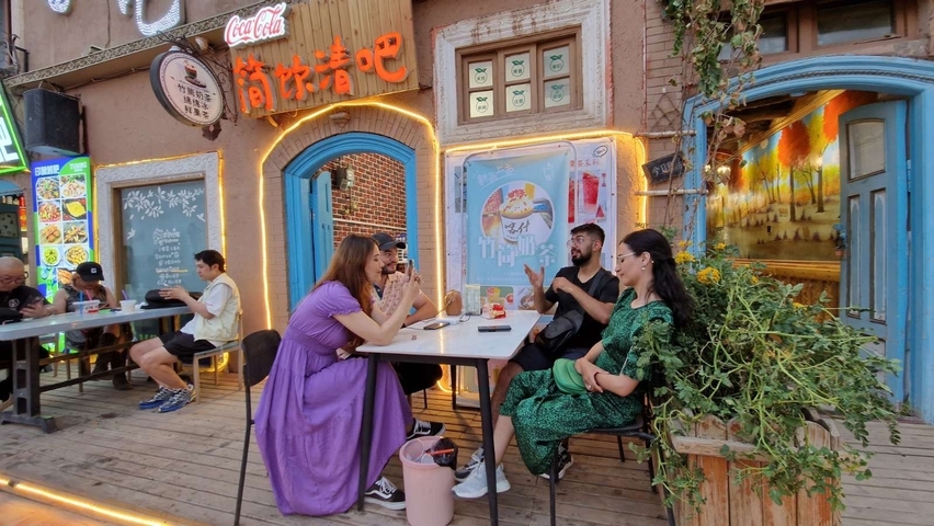 People sitting at an outdoor cafe with colorful decor.