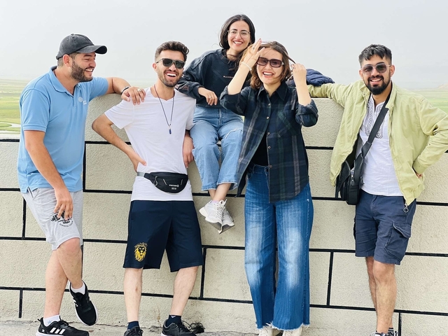 Group of friends posing casually against a scenic background.