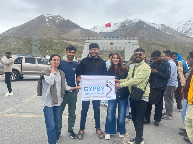Group of travelers holding a banner in front of a mountain pass.