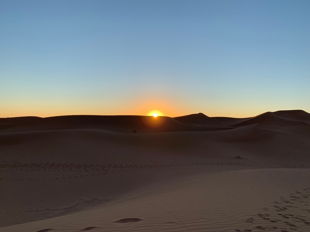      Desert dunes with the sun setting on the horizon.
  