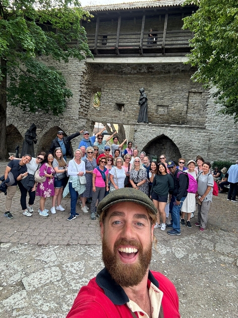 Large group of people posing outdoors in front of historic ruins.