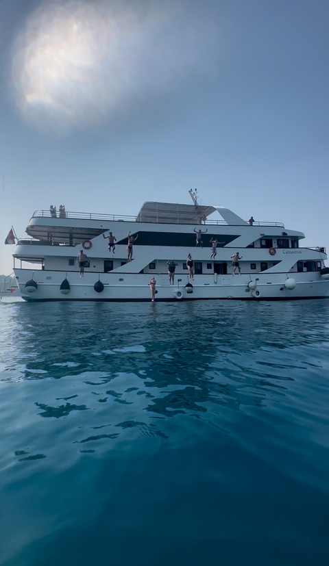       People jumping off a yacht into the sea.
  