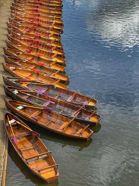       Colorful boats docked along a calm river.
  