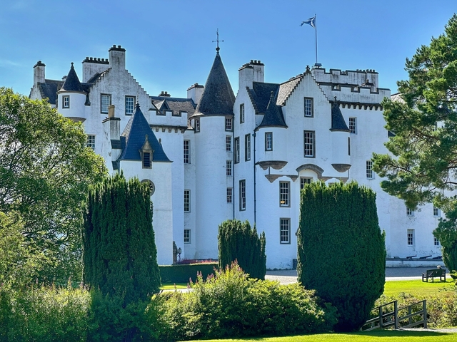 White castle with turrets surrounded by lush greenery.