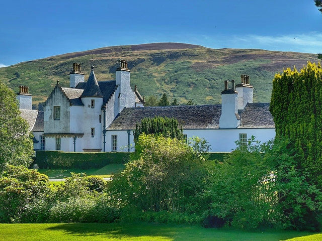       Charming white house with chimneys set in lush countryside.
  