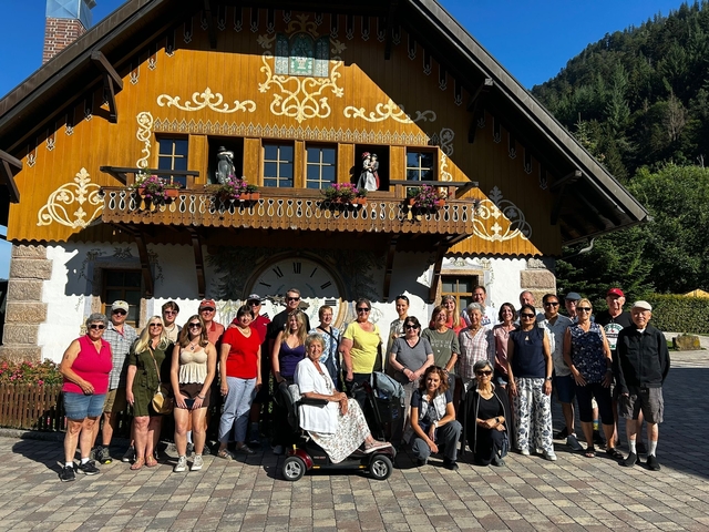 Group of tourists posing outside a traditional wooden house