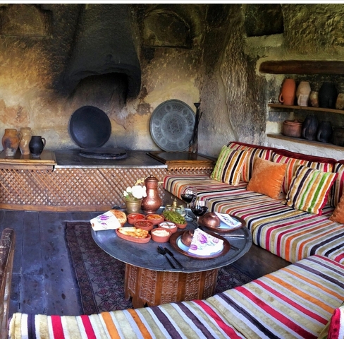       Indoor setup with traditional seating and food served on a low table
  