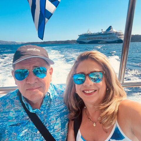       A couple on a boat with a cruise ship in the background
  