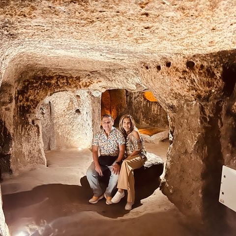       Couple sitting inside a cave-like structure.
  
