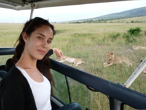      Woman on safari with lions in the background.
  