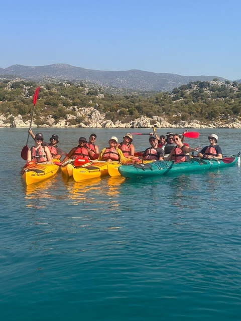       Group kayaking with life jackets on clear water.
  