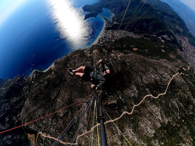       Person paragliding over a scenic coastline.
  