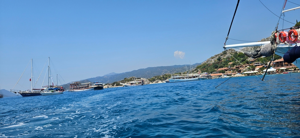       Boats in a coastal harbor with mountains in the background.
  