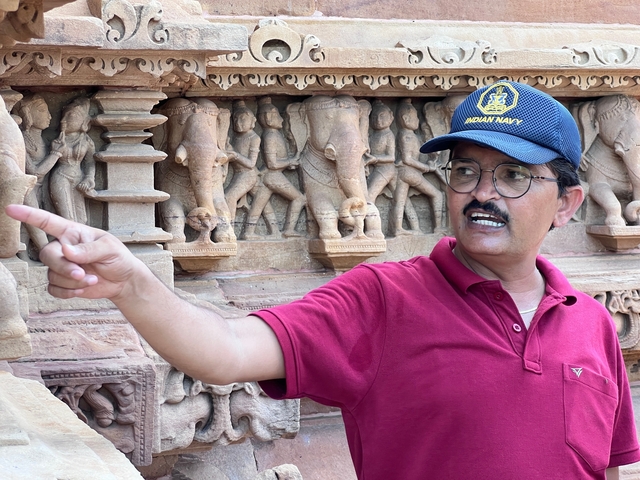       Person pointing at ancient stone carvings.
  