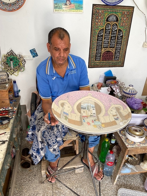       Artisan painting a large decorative plate
  
