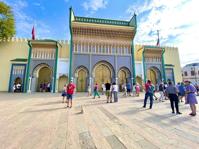       Tourists in front of an impressive building with ornate doors.
  