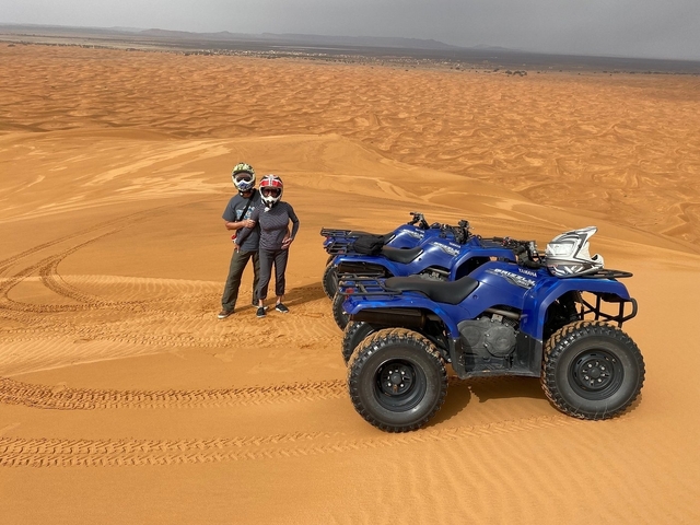       People on quad bikes in a desert landscape.
  