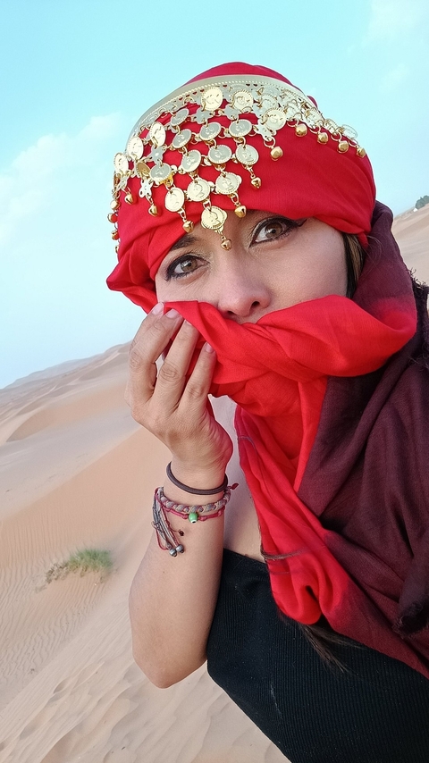       Woman in a red scarf posing in a desert.
  