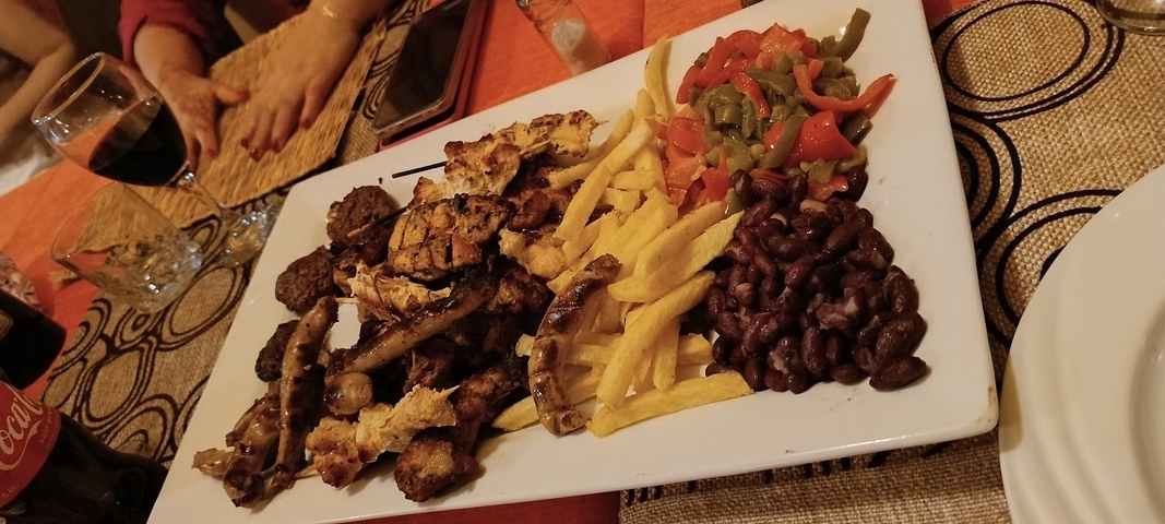       Plate of grilled meats, fries, and vegetables.
  