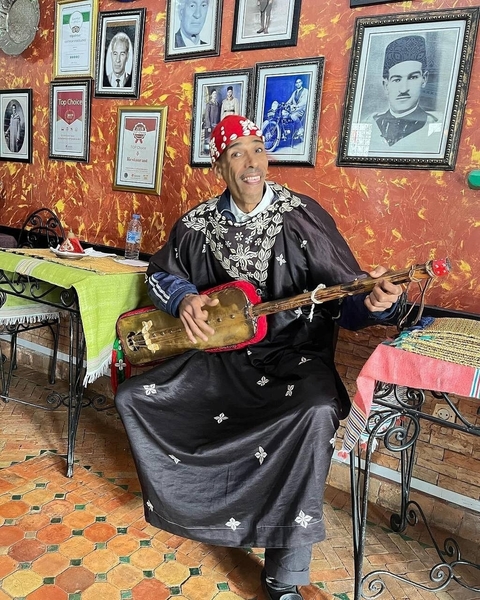       Musician playing a traditional instrument indoors.
  