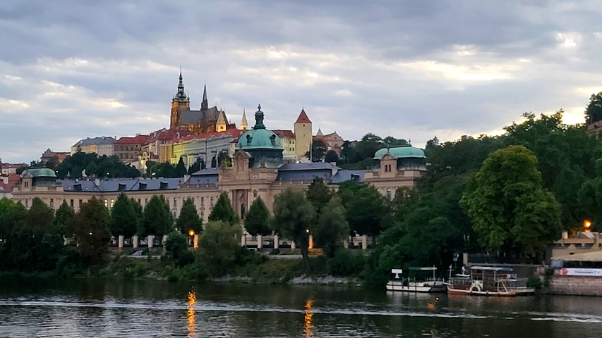       Riverside view of historic buildings and a church.
  