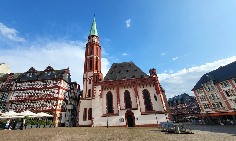       Historic town square with a church and colorful buildings.
  