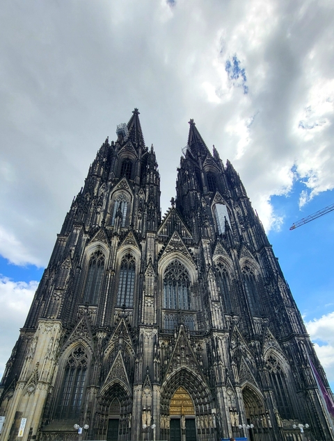       Gothic cathedral towers against a cloudy sky.
  