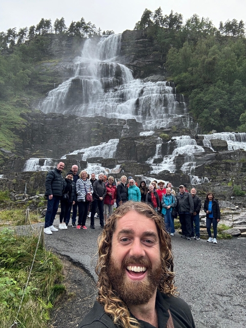 A group of people in front of a waterfall.