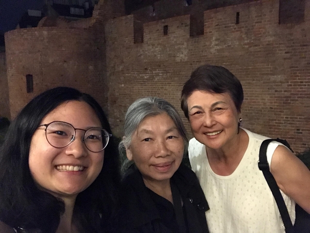 Three women standing close together at night.