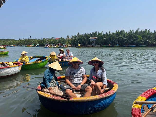       People in small boats wearing conical hats on a river surrounded by tropical flora.
  